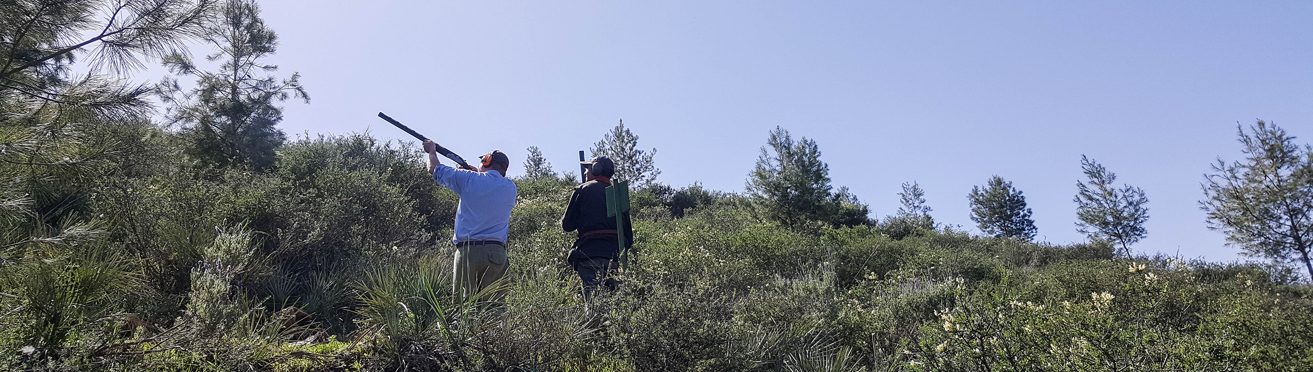 Two hunters aiming shotguns on a green Atlas slope