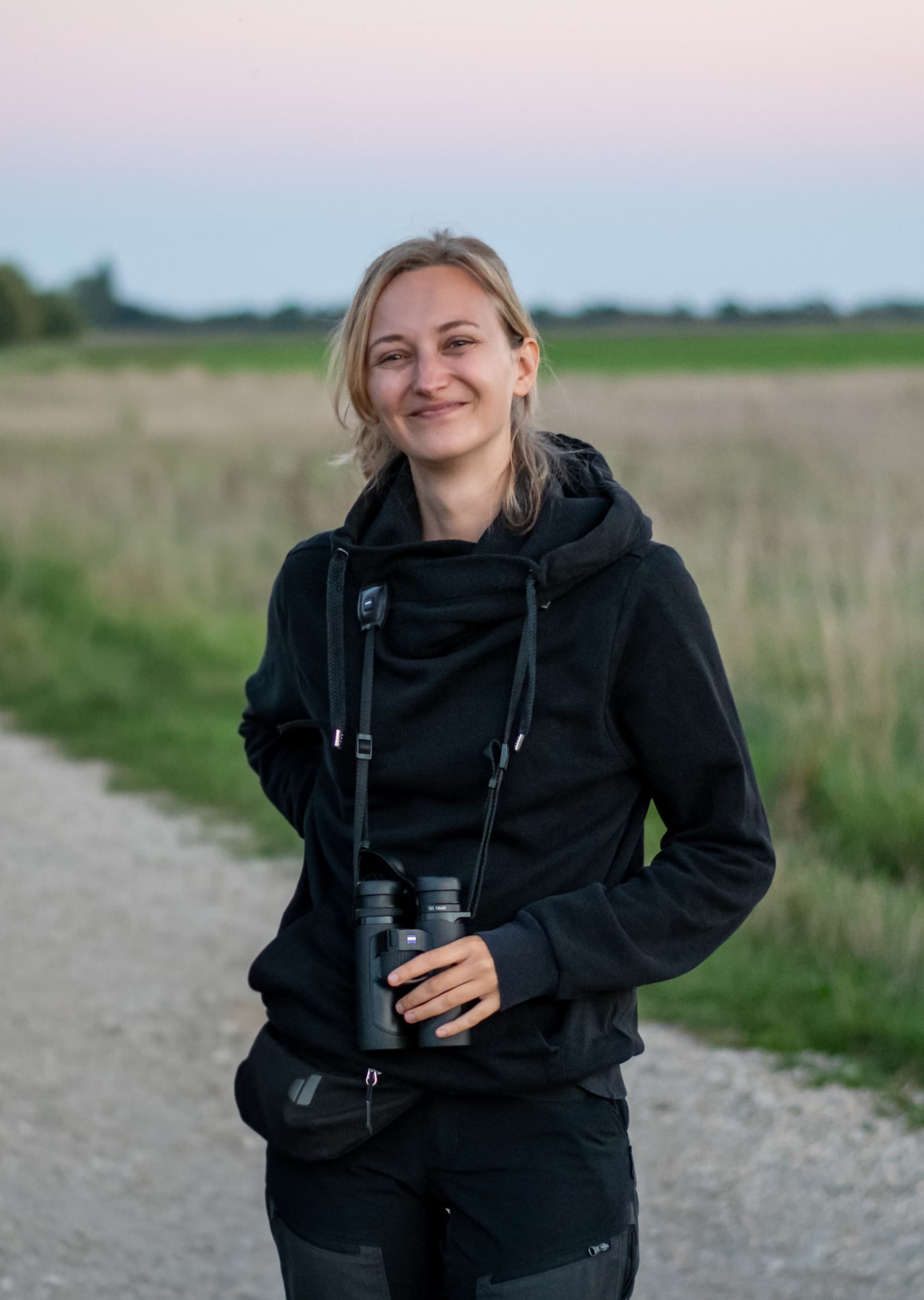 Alexandra outdoors with binoculars hanging around her neck.
